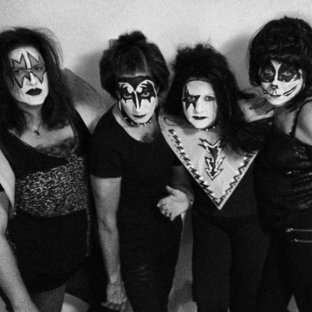 Black and white photo of four adults in KISS-inspired face painting by About Face Painting, Denver